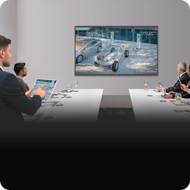 A man using his tablet to control a Createboard from his seat while in a meeting.